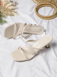Detailoverzicht van crèmekleurige sandalen met vierkante neus, dunne bandjes en hakje