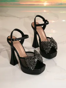 Close-up of black mesh high heel sandals with sparkling rhinestone bow detail