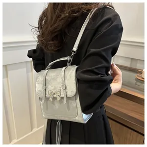 Silberne kleine Umhängetasche mit Schmetterlingsschleife an asiatischem Model