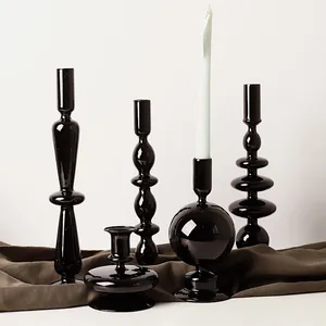 Série de bougeoirs en verre noir sur tissu sombre pour une déco de table chic.