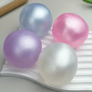 Close-up of four colorful pearlescent moldable stress balls on a wavy white tray