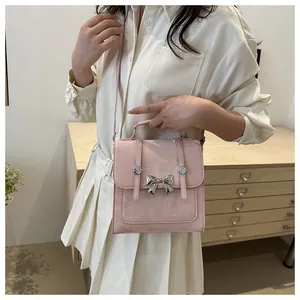 Elegante kleine rosa quadratische Tasche mit Schleifendetail, von einem Modell gehalten