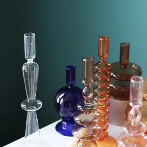 Gros plan détaillé de divers bougeoirs en verre géométriques colorés sur surface blanche