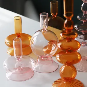 Vue rapprochée détaillée de bougeoirs et vases artistiques en verre coloré de table.