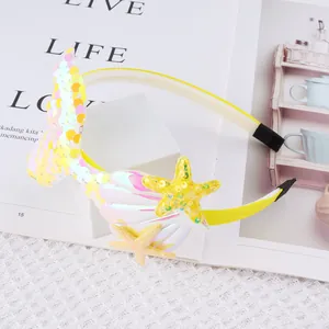 Detail of a yellow mermaid tail headband with iridescent sequins, shell, and starfish.