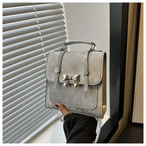 Detailansicht eines silbernen Rucksacks mit einer dekorativen Schleife aus Metall