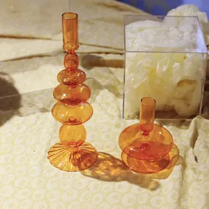 Gros plan de bougeoirs artistiques en verre orange sur un fond de tissu à motifs