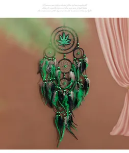 Vista detallada de un atrapasueños hecho a mano con hojas verdes, plumas y cuentas