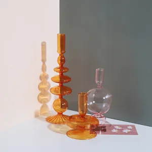 Vue détaillée de bougeoirs et vases en verre coloré ambre et rose pour décoration de table.