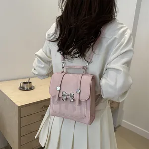 Eleganter rosa Mini-Rucksack für Damen mit silbernem Schleifenakzent und Tragegriff.