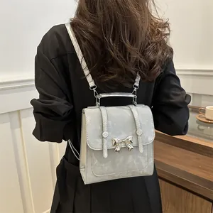 Eleganter silberner Metallic-Rucksack mit Schleifenakzent, getragen über einem Kleid