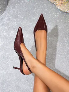 Close-up van bordeauxrode slingback kitten heels met spitse neus op zilveren glitter