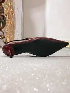 Detailopname van de zwarte loopzool en het bordeauxrode lakleer van een kitten heel sandaal.