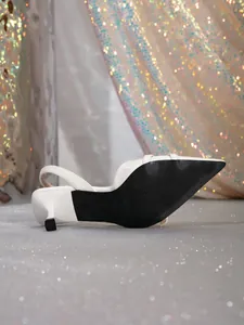 Close-up of white slingback kitten heel showing textured non-slip black sole detail