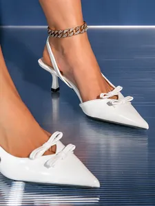 Close-up of white pointed toe kitten heel sandals with elegant double bow details