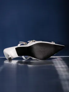 Unteransicht eleganter weißer spitzer Pumps mit Pfennigabsatz und Riemchendetail.