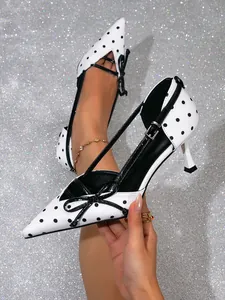 Primer plano de tacones blancos con lunares negros y lazo sobre fondo brillante