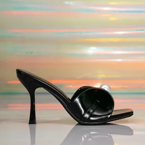 Eleganti sabot neri con tacco alto, grande perla decorativa e tacco a spillo sottile.