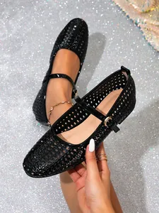 Detailaufnahme schwarzer Mary Jane Ballerinas mit Lochmuster und Schnallenverzierung.