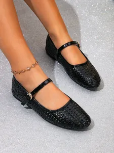 Nahaufnahme schwarzer flacher Mary-Jane-Schuhe mit dekorativem Lochmuster.