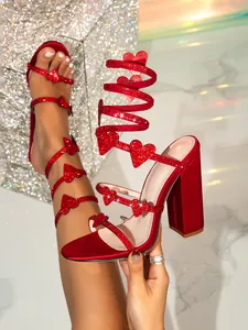 Detailansicht glamouröser roter Sandalen mit Strassherzen und spiralförmigen Riemen