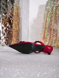 Vista detallada que muestra la suela negra y el charol rojo de este zapato de tacón en punta.