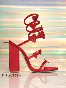 Detaillierte Makroansicht von roten Strass-Sandalen mit Herzanhängern und Spiralabsatz