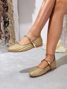 Detailansicht der goldfarbenen flachen Mary-Jane-Schuhe mit dekorativem Lochmuster.