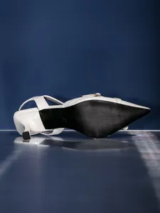 Vista dettagliata della suola nera e del tacco a rocchetto dei sandali bianchi slingback
