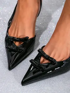 Close-up detail of black patent leather pointed shoes with elegant double bow design