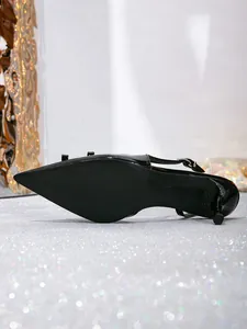 Detailed view of black patent leather slingback heels showing textured non-slip sole