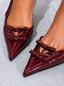 Detailed macro view of burgundy patent leather pointed-toe pumps with elegant double bow
