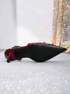 Detail of elegant burgundy pointed-toe slingback heel with a bow on glitter background.