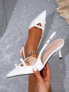 Detail of elegant white pointed-toe slingback heels with dainty double bows
