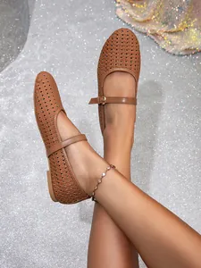 Nahaufnahme brauner Mary Jane Ballerinas mit Lochmuster und Schnallenriemen auf Glitzergrund