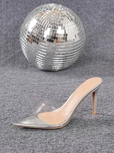 Primo piano di sandalo stiletto argento con cinturino trasparente e punta