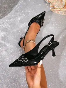 Primer plano de zapatos de tacón negro con punta fina y correas de hebilla decorativas