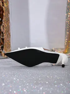 Close-up view of elegant white pointed-toe slingback kitten heels with a black sole