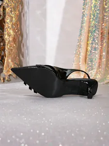 Vista detallada de un zapato destalonado de charol negro con tacón de aguja y punta fina.