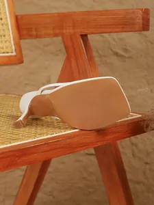 Gedetailleerde opname van de zool en de hak van de witte sandaal op een houten stoel