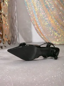 Elegantes tacones de aguja negros de punta fina con acabado en charol brillante.