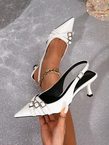 Primer plano de elegantes tacones blancos destalonados con punta y hebillas metálicas