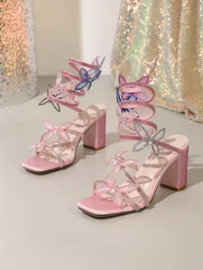 Détail des sandales à lacets en satin rose avec décorations papillons en strass étincelants.