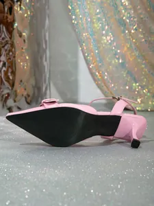 Vista detallada de zapatos elegantes de tacón rosa con punta fina y suela negra clásica