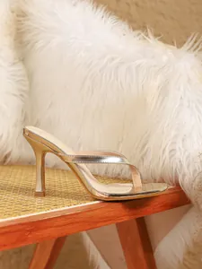 Gedetailleerd zijaanzicht van elegante gouden sandalen met hoge hakken op een rotan stoel