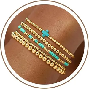 Gedetailleerd overzicht van stapelbare gouden en turquoise kralenarmbanden met kruis