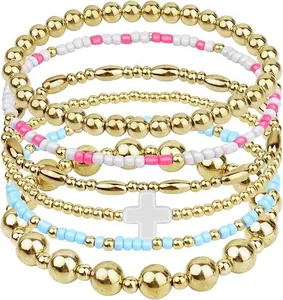Stapelbare elastische kralenarmbandenset met gouden kralen en een witte kruishanger