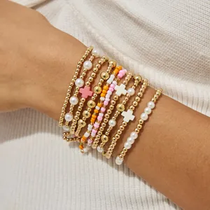 Close-up van een set stapelbare elastische kralenarmbanden met gouden kralen en parels