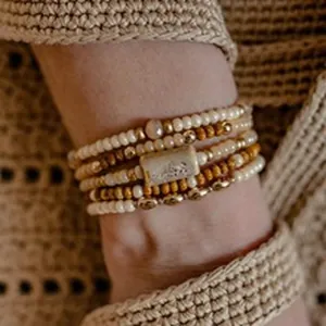 Close-up of bohemian multi-layer beaded bracelet set worn on wrist with beige knitwear