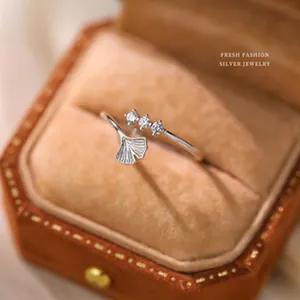 Detailed view of silver ginkgo leaf ring with sparkling clear stones in a velvet box